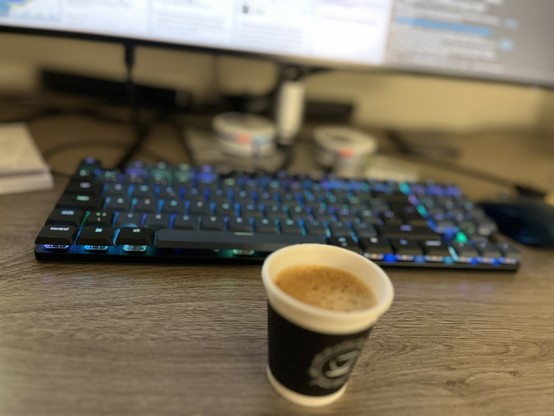 A cup of espresso in front of a keyboard.